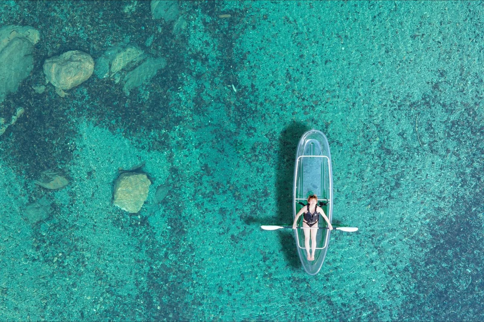 Kayak à coque transparente vu du ciel sur une eau turquoise peu profonde