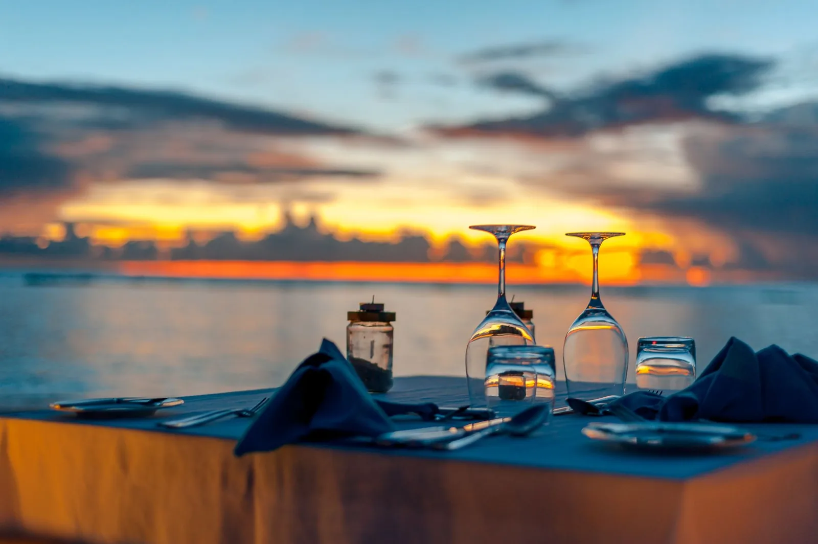 Table dressée pour deux face à l'océan Indien au coucher du soleil, pour un dîner romantique sur la plage