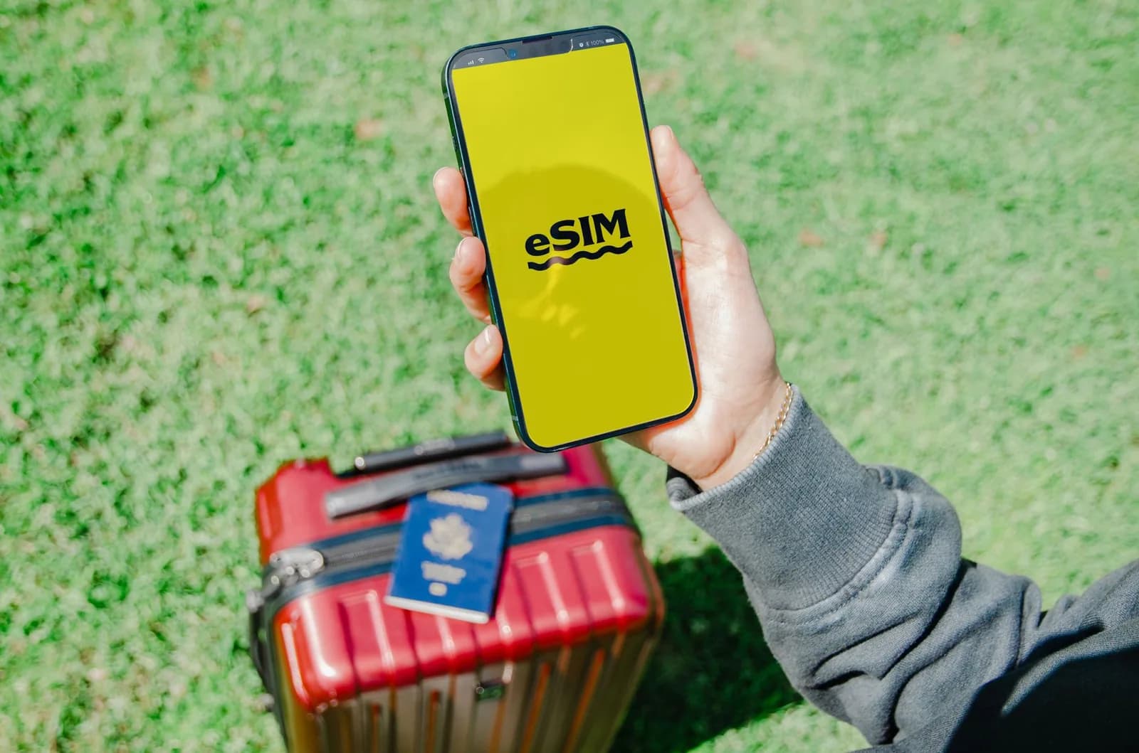Smartphone affichant un écran eSIM, posé au-dessus d'un passeport et d'une valise de voyage