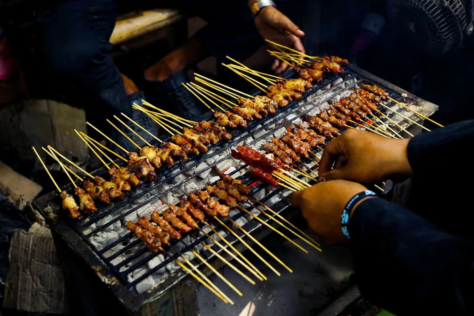 Brochettes de viande grillées au charbon sur un stand de street food, le soir