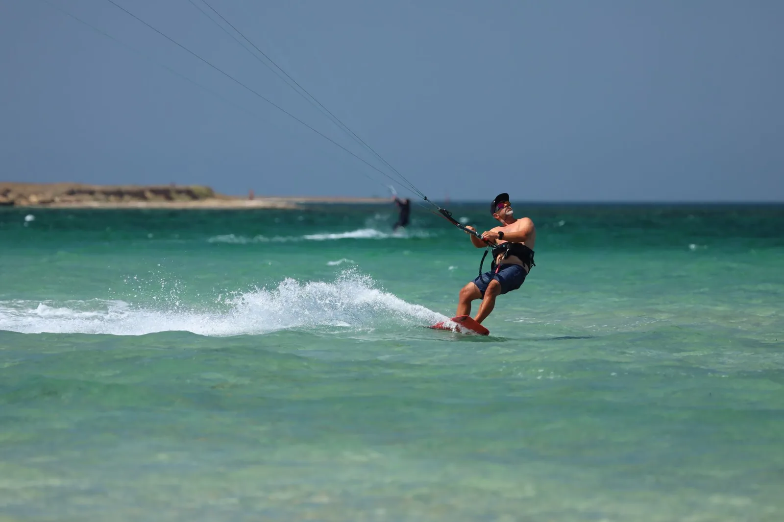 Kitesurfeur glissant sur un lagon turquoise peu profond par vent soutenu à Zanzibar