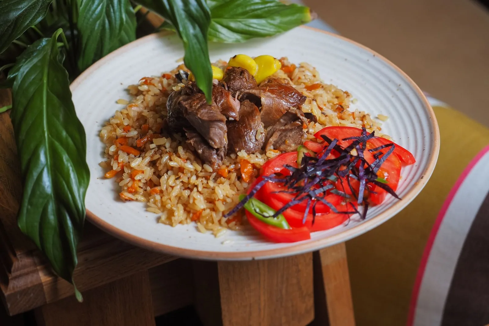 Assiette de pilau, riz brun aux épices servi avec des morceaux de viande et des tomates