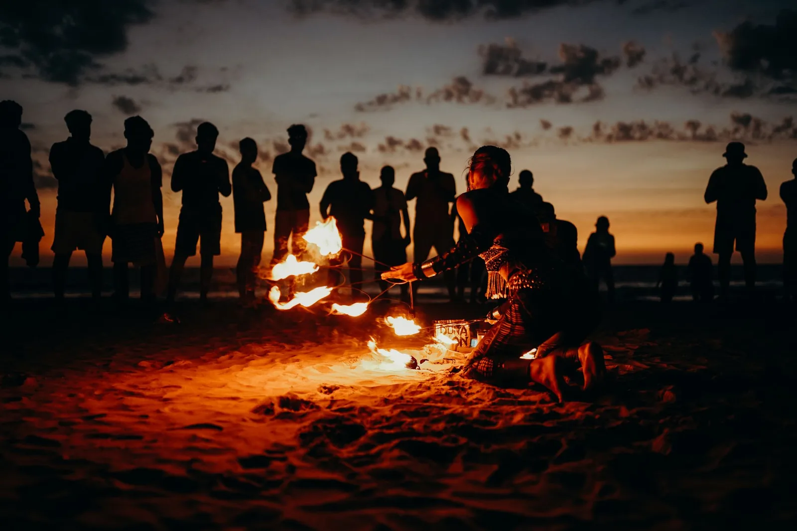 Spectacle de feu au crépuscule devant un public sur le sable, ambiance des soirées de fin d'année sur les plages du nord de Zanzibar