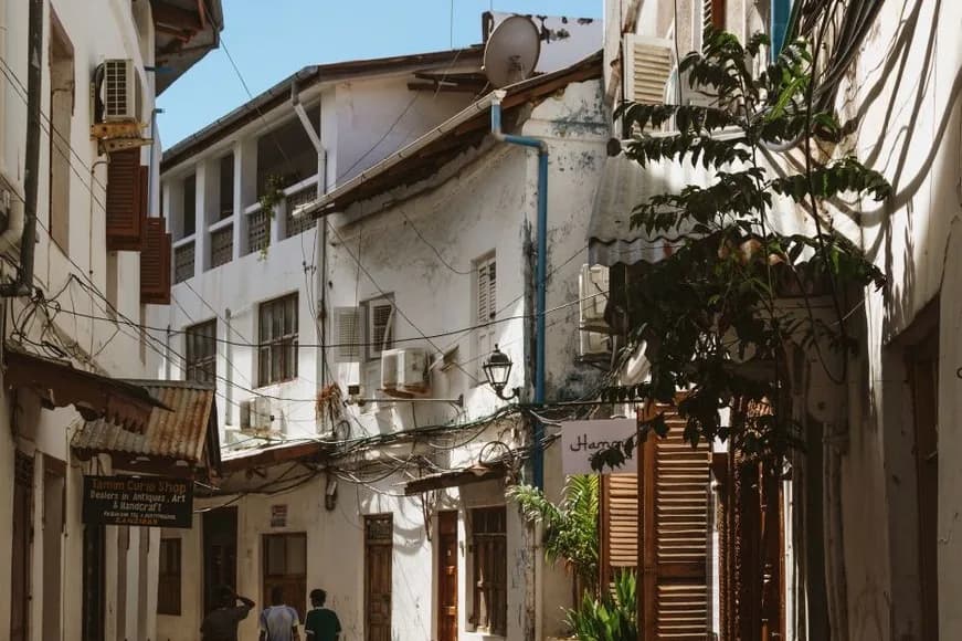 Ruelle de la vieille ville de Stone Town à Zanzibar, façades blanches à volets de bois et enseignes