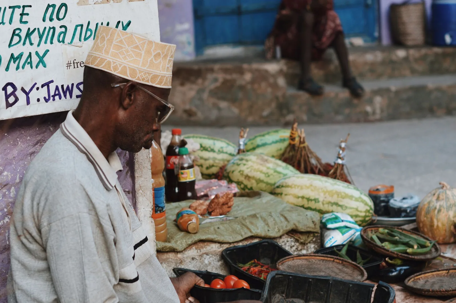Vendeur de rue zanzibari derrière son étal de fruits et légumes à Stone Town