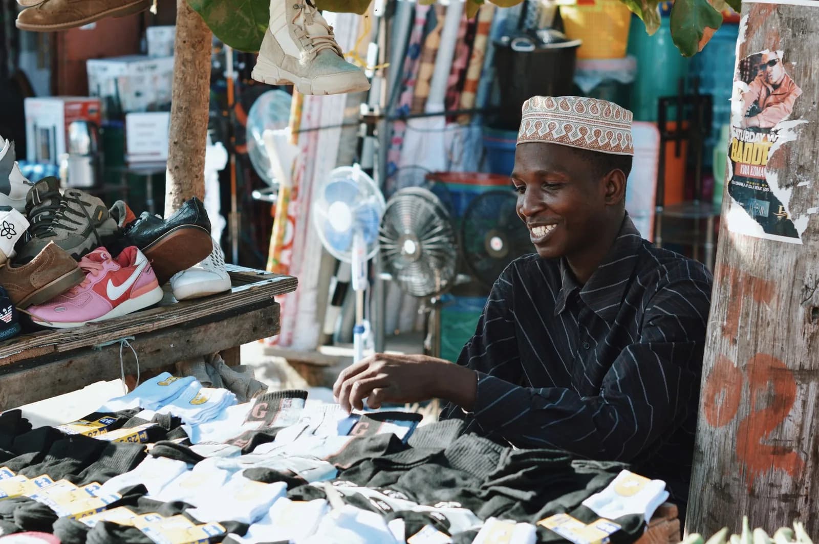 Vendeur souriant derrière son étal de chaussettes et de chaussures sur un marché de Zanzibar