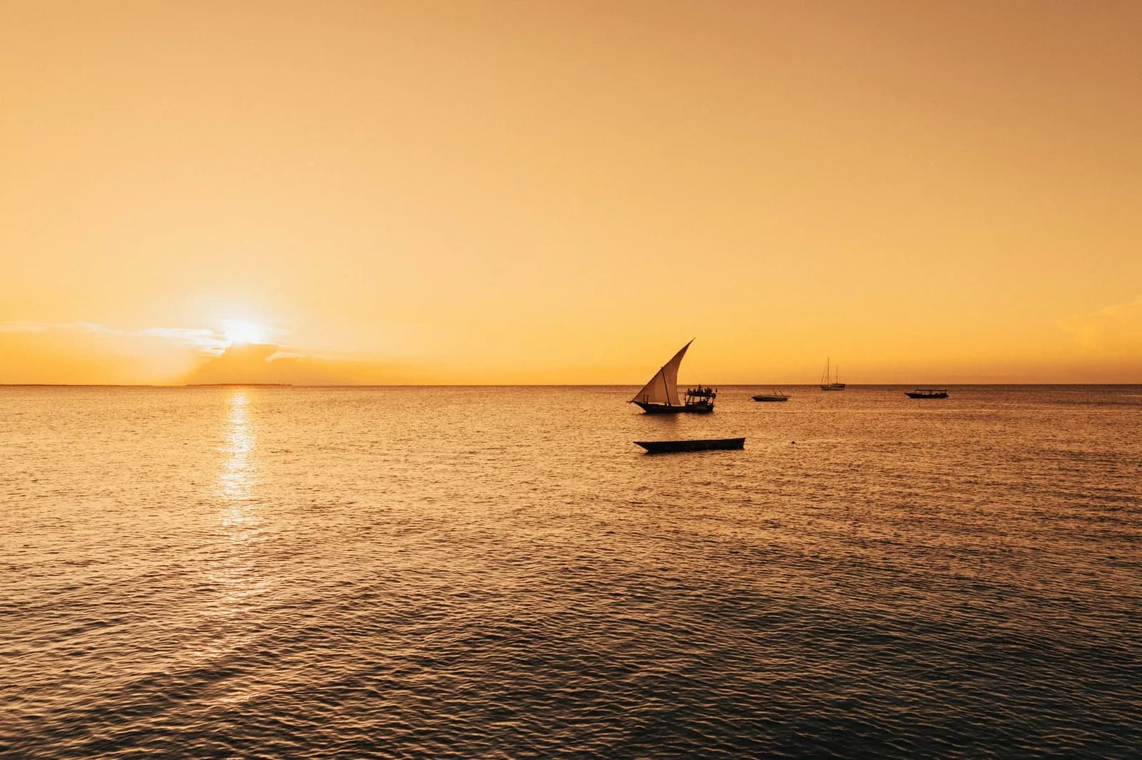 Coucher de soleil doré sur l'océan Indien avec des dhows traditionnels au large de Zanzibar